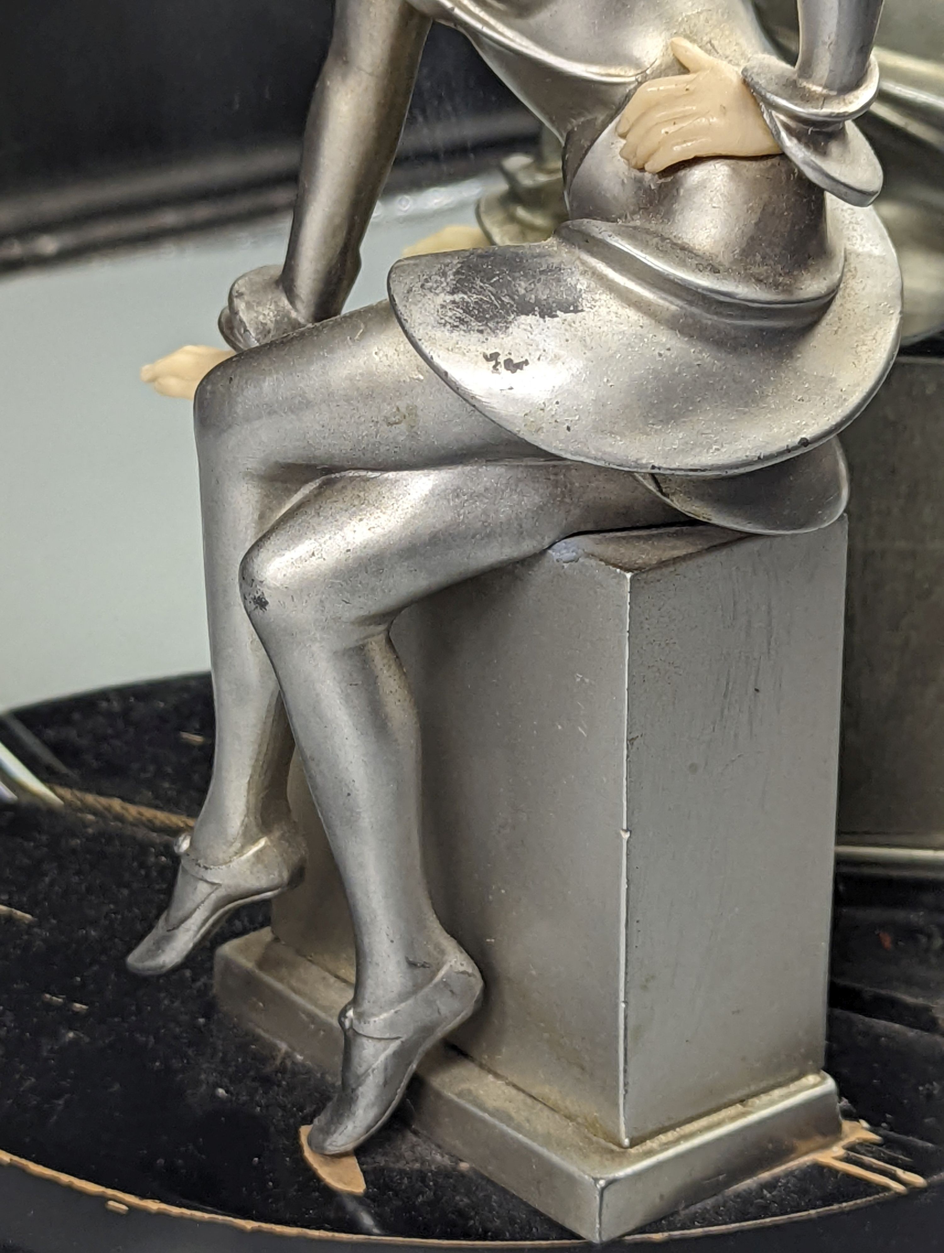 An Art Deco style patinated spelter and faux ivory figural mantel mirror, 31cm